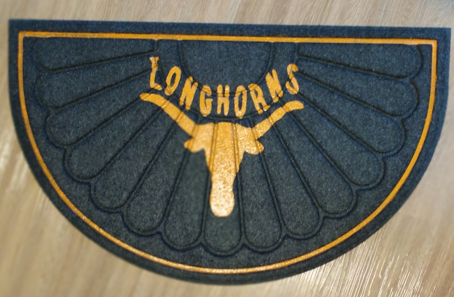 Gold Longhorns logo on a black textured mat

