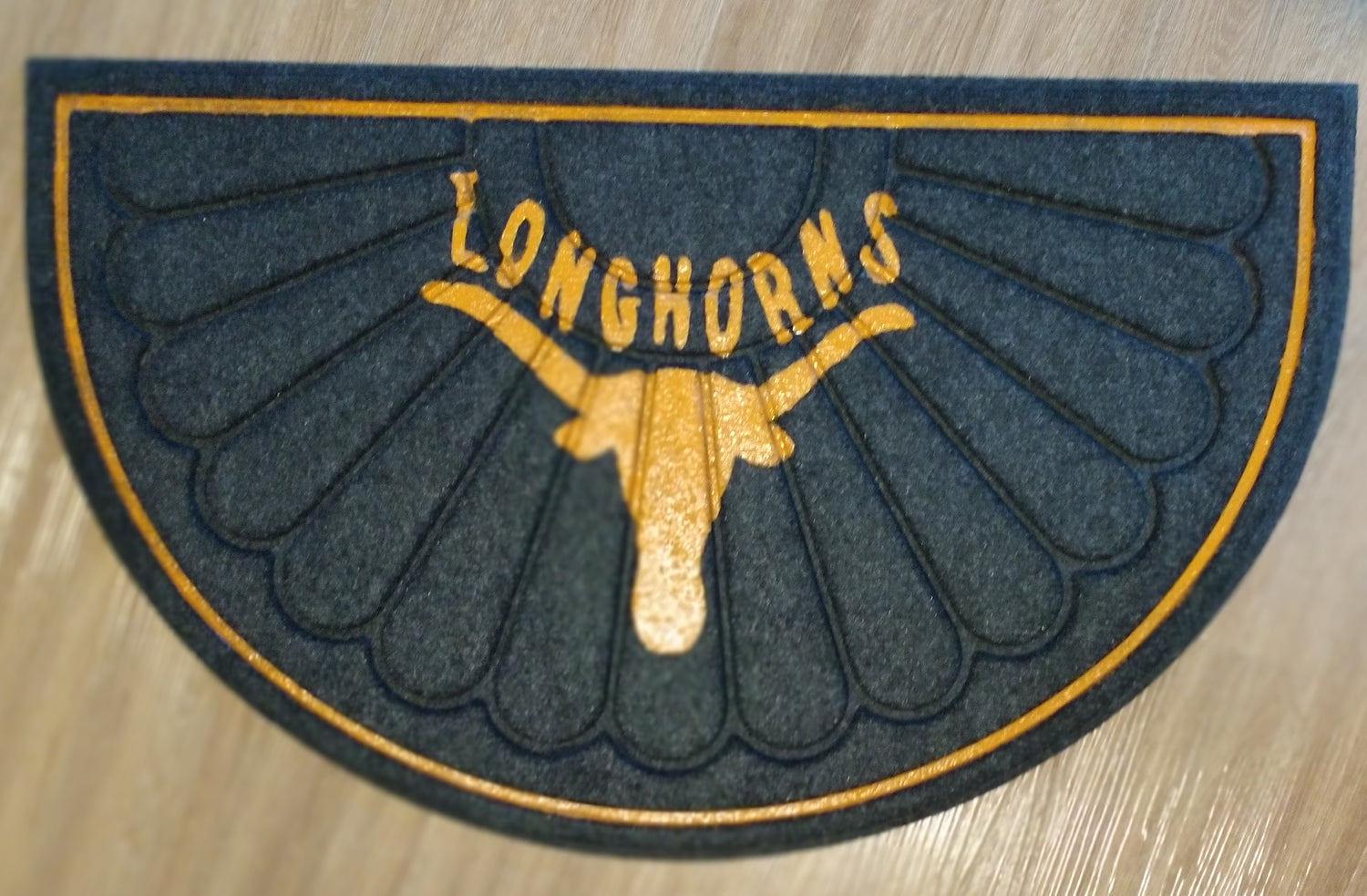 Gold Longhorns logo on a black textured mat

