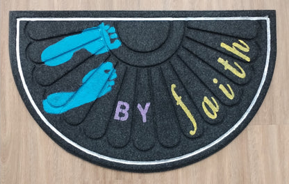 Decorative mat with blue feet, purple 'BY', and yellow 'faith' on a wooden floor.