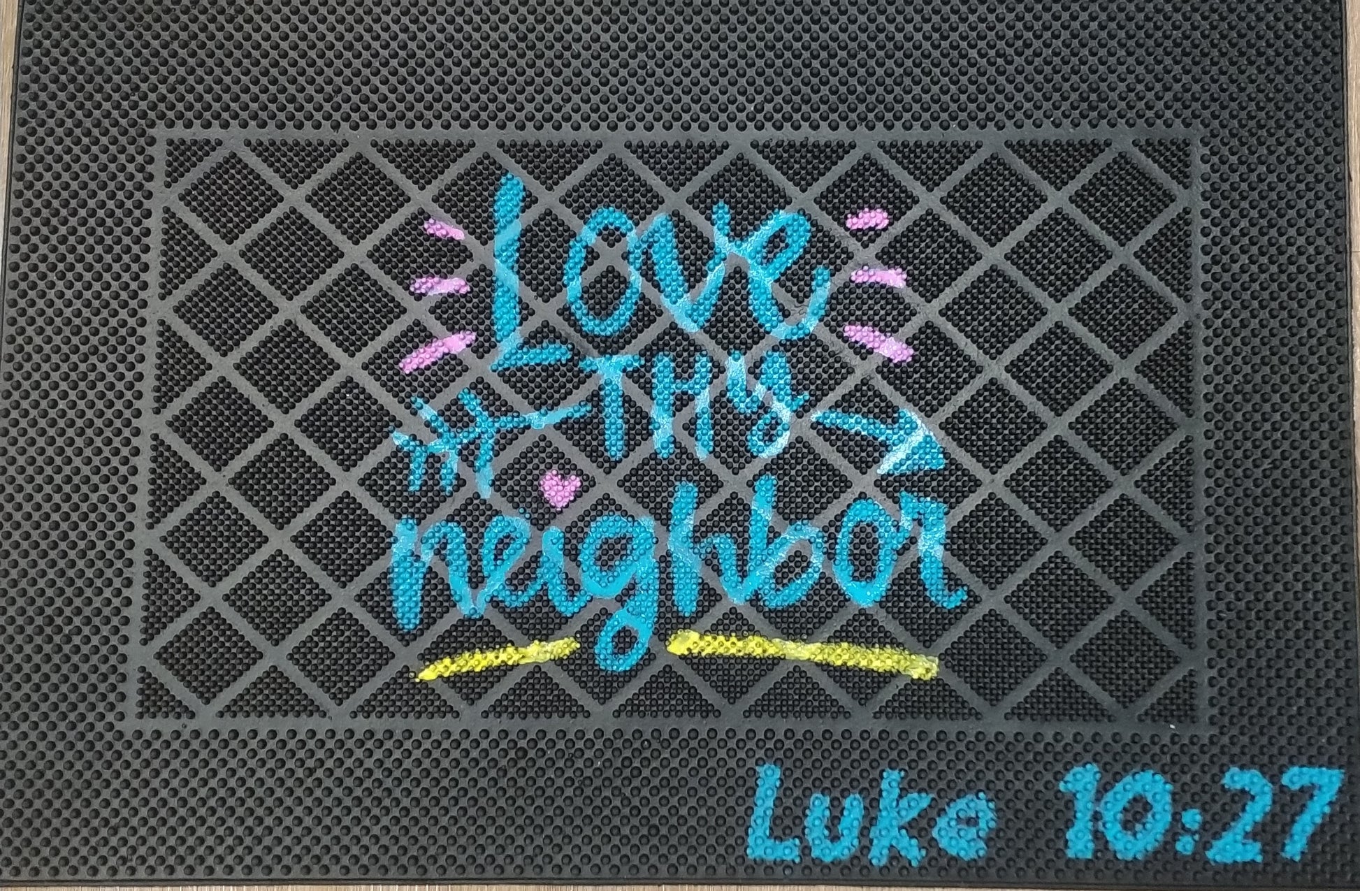 Doormat with 'Love your neighbor' text and Bible verse on a textured surface
